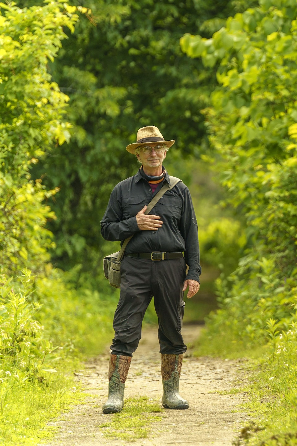 Un homme debout dans un sentier au milieu d'une forêt.